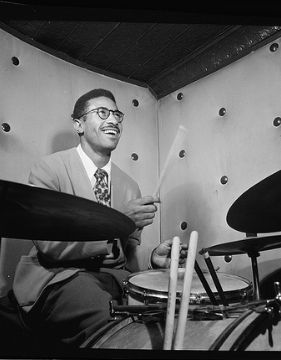 A black and white photo of Max Roach playing the drums