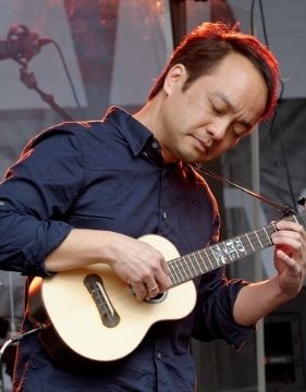 Uke player Daniel Ho playing a ukulele on stage.