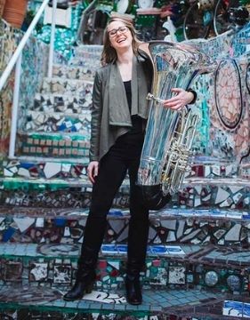 Female tuba player Carol Jantsch on the steps while holding her tuba