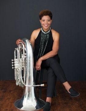 Famous tuba player Velvet Brown on a chair with her tuba by her side