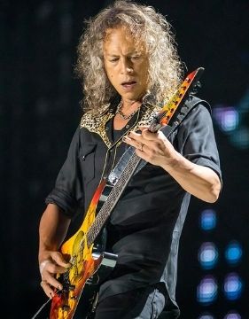 A picture of guitar player Kirk Hammett playing his guitar on stage.