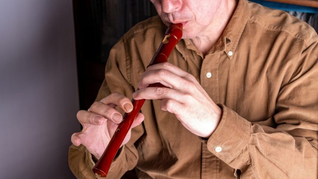 A man playing a recorder, a woodwind instrument