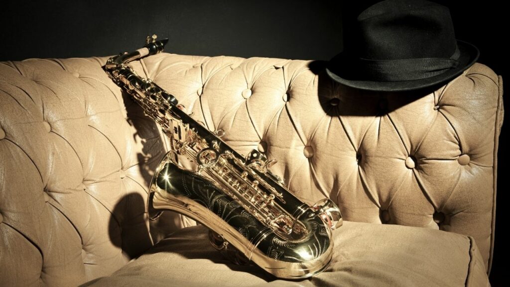 A shiny saxophone on a leather sofa
