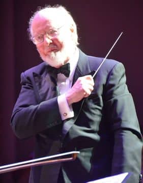 photo of John Williams conducting on stage.