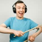 Man hearing music with drumsticks