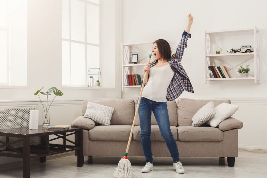 Happy Woman Cleaning Home Singing At Mop Like At Microphone