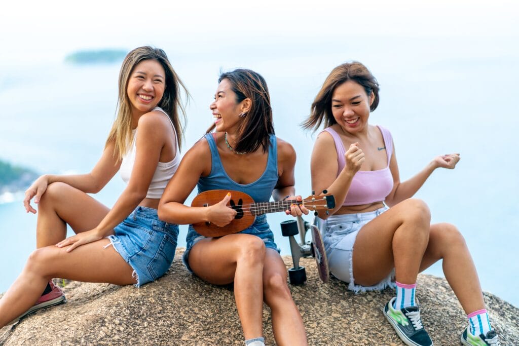 Group Of Asian Woman Sitting On Mountain Peak Playing Ukulele