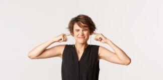Bothered Young Woman Shut Ears With Fingers And Squinting From